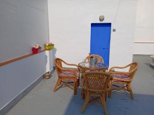 una mesa con 4 sillas y una puerta azul en Apartamento de las Flores en Conil, en Conil de la Frontera