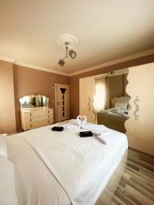 Seabird Suite Apart Hotel في طرابزون: غرفة نوم مع سرير أبيض كبير مع مرآة