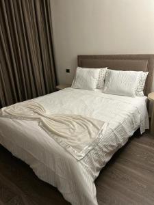 a bed with a white comforter and pillows at Appartement Priv&eacute; au Vizir Center Marrakech in Marrakech