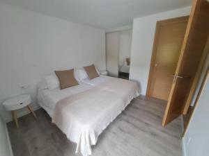sypialnia z białym łóżkiem i drewnianą podłogą w obiekcie Casa Cainzal w mieście Foz