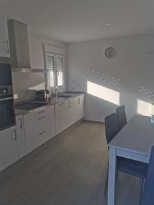 kuchnia z białymi szafkami oraz stołem i krzesłami w obiekcie Casa Cainzal w mieście Foz