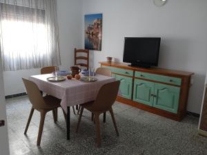 comedor con mesa con sillas y TV en Apartamento de las Flores en Conil, en Conil de la Frontera