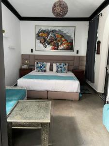 1 dormitorio con 1 cama y una pintura en la pared en Riad El Palacio & Spa Chaouen en Chefchaouene