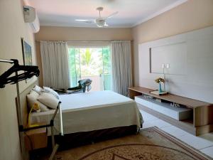 um quarto com uma cama, uma secretária e uma janela em Linda casa com piscina aquecida e ar condicionado a 1h do RJ em Guapimirim