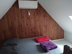 a bed in a room with a wooden wall at Gite la forêt in Chénérailles