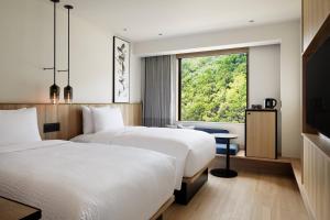 two beds in a hotel room with a window at Fairfield by Marriott Wakayama Kushimoto in Kushimoto