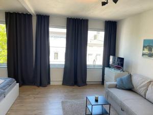 a living room with a couch and two windows at Ferienwohnung Hansezauber Lübeck in Lübeck