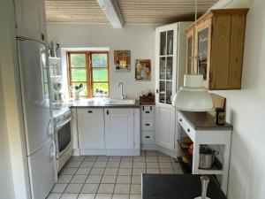uma cozinha com armários brancos e um frigorífico branco em A true nature pearl in idyllic surroundings but close to the city em Holbæk