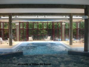 Hotel Bienestar Termas de Moncao في مونكاو: حمام سباحة كبير مع الكثير من النوافذ