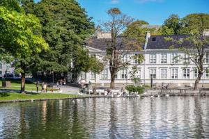 a building next to a lake in front of a building at Charming Rooftop Apartment in Heart of Stavanger in Stavanger