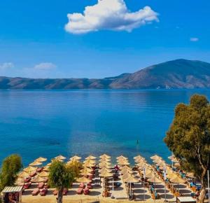 a beach with chairs and umbrellas on the water at Orik Apartament in Vlorë
