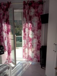 a bedroom with pink curtains and a sliding glass door at Orik Apartament in Vlorë