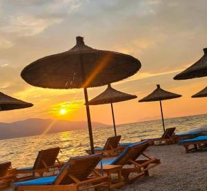 a group of beach chairs and umbrellas on the beach at Orik Apartament in Vlorë +7 photos