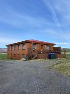 a large wooden building in a field next to a parking lot at Guesthouse Helluland in Þingeyjarsveit