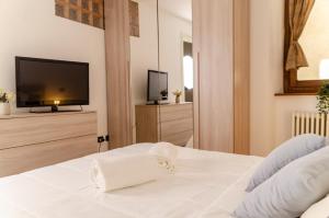 a bedroom with a white bed with a flat screen tv at K2 Apartment in Aosta