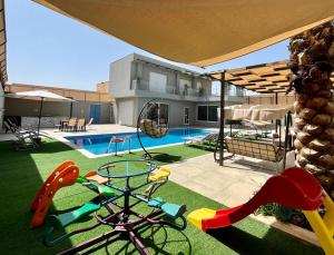 een achtertuin met een zwembad en een speeltuin met bij Gloria Chalet in Al Rama