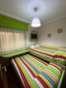 2 camas en una habitación con rayas coloridas en Apartamento Marichu, en Melide