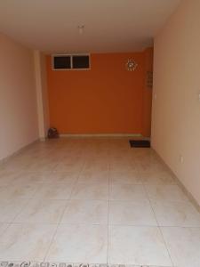 Habitación vacía con paredes de color naranja y suelo de baldosa. en Hermoso Alojamiento, en Choachí