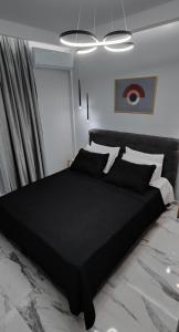 a bedroom with a black bed with a black comforter at Cozy Garden View Apartment in Paralia in Paralia Katerinis