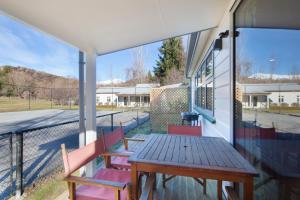 un patio con una mesa de madera y sillas en un porche en Willowbrook Country Apartments, en Arrowtown