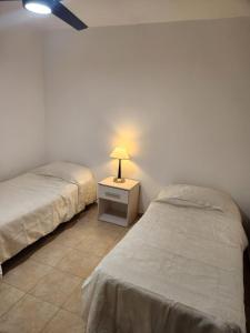 1 dormitorio con 2 camas y mesita de noche con lámpara en Departamento Capital en La Rioja