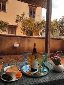 a table with a bottle of wine and wine glasses at La casa dei pesci dipinti in Castelluzzo