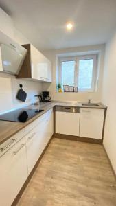 a kitchen with white cabinets and a sink and a window at ST-Apartment Charming 1 mit Terrasse und Garten, 3 Zimmer in Geislingen in Geislingen an der Steige