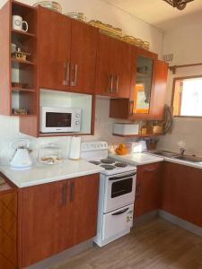 a kitchen with wooden cabinets and a white stove top oven at Serene & quiet 2- Bedroom Cottage Statelodge area in Shimwansa