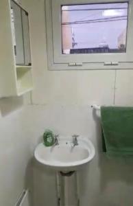 lavabo blanco en un baño con ventana en Experiencia la Rinconada en Comodoro Rivadavia