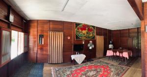 a room with wooden walls and a table and a rug at Koto Hilalang Homestay in Bukittinggi