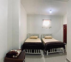 2 Betten in einem Zimmer mit weißen Wänden in der Unterkunft Bukittinggi Homestay in Bukittinggi
