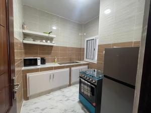 La cuisine est équipée d'un réfrigérateur noir et d'un évier. dans l'établissement Résidence KANN, à Dakar