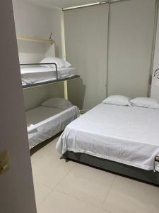 two beds in a room with white sheets and pillows at Laguna club zona norte - se renta con vehículo in Cartagena de Indias