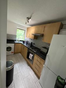 a kitchen with wooden cabinets and a white refrigerator at Lovely one bedroom apartment in Thornton Heath