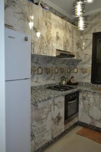 Appartement très bien meublé - Résidence sécurisée في أغادير: مطبخ مع ثلاجة بيضاء وجدار من الرخام