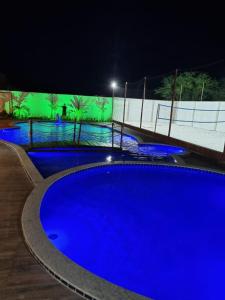 PIRANHAS HOTEL في ببرانا: حمام سباحة أزرق كبير في الليل مع