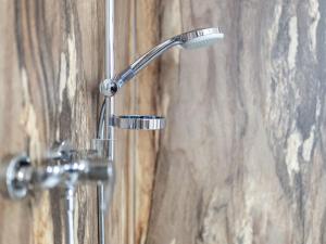 a shower head in a bathroom with a wooden wall at Kronenburger Comfort Bungalow in Hallschlag +25 photos