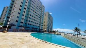 a swimming pool in front of a large building at Apartamento BEIRA-MAR com 2 quartos in Maceió