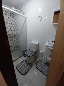 a bathroom with a toilet and a shower and two mats at Casa 4 in Campos dos Goytacazes