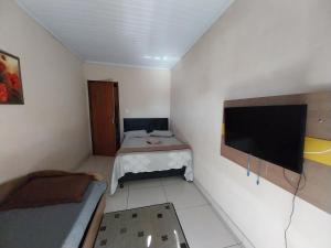 um pequeno quarto com uma cama e uma televisão de ecrã plano em Casa 4 em Campos dos Goytacazes