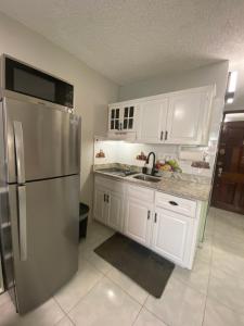 a kitchen with white cabinets and a stainless steel refrigerator at Ocho Rios Vacation Resort Property Rentals in Ocho Rios