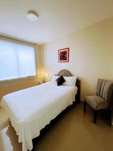 a bedroom with a bed and a chair and a window at Suites Apart Piura in Piura