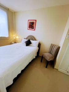 - une chambre avec un lit blanc et une chaise dans l'établissement Suites Apart Piura, à Piura