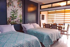 2 Betten in einem Schlafzimmer mit einem Tisch und Stühlen in der Unterkunft Marqis Sunrise Sunset Resort and Spa in Baclayon