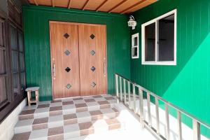 Habitación verde con puerta de madera y suelo a cuadros. en Guest house yamahide, en Tatsugo