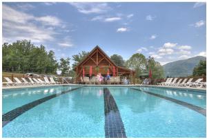 a large swimming pool with chairs and a building at GYPSY ROAD - Privacy! Log Cabin with Hot Tub, WiFi, DirecTV and Arcade in Sevierville