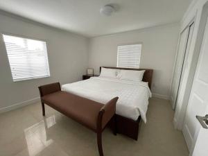 um quarto branco com uma cama e um banco em Villa Capri Cottage in the heart of Miami em Miami