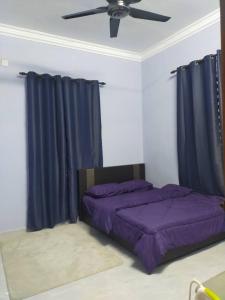 una camera con 2 letti, lenzuola viola e ventilatore a soffitto di Homestay penghulu noor a Pasir Puteh