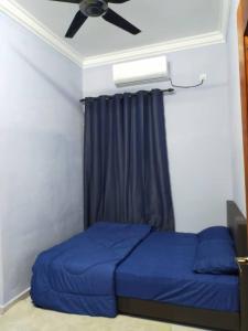 um quarto com uma cama azul e uma ventoinha de tecto em Homestay penghulu noor em Pasir Puteh