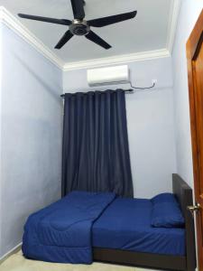 una camera con letto blu e ventilatore a soffitto di Homestay penghulu noor a Pasir Puteh